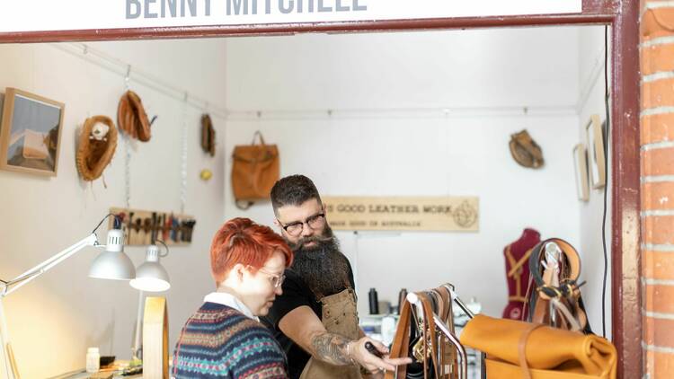 A man showing a woman how to make leather belts.