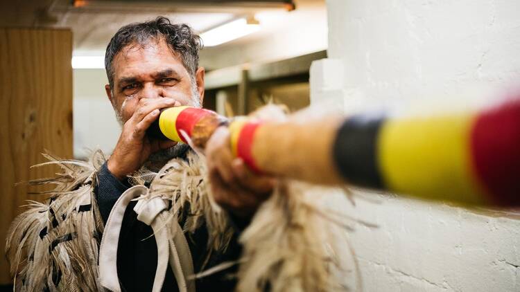 An Indigenous man with a didjeridoo