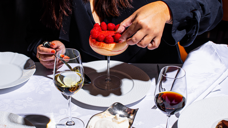 A woman eating a raspberry dessert from a white table