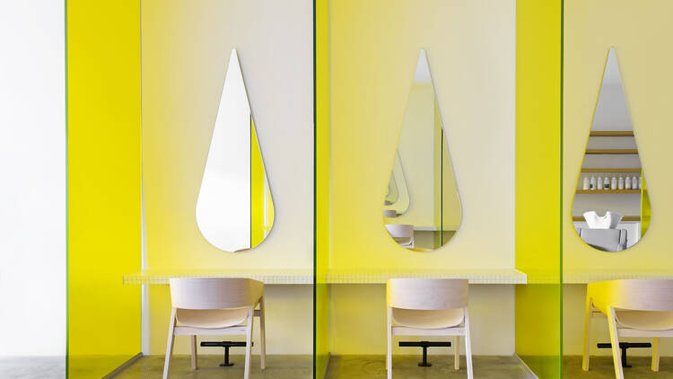 Booths with teardrop shaped mirrors and chairs.