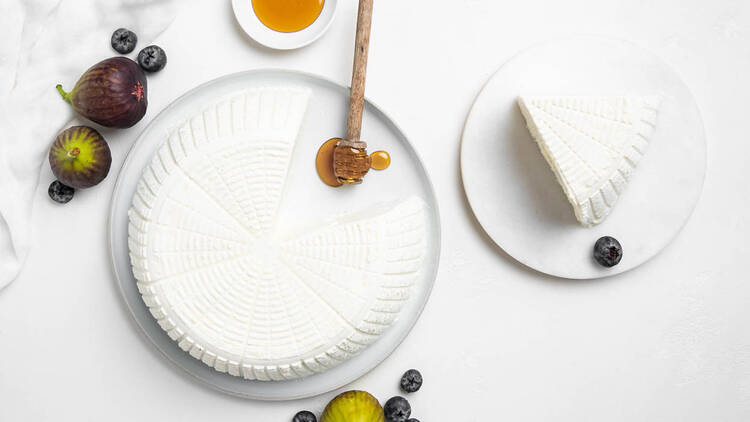 An overhead shot of a big round of ricotta with a slice cut out.