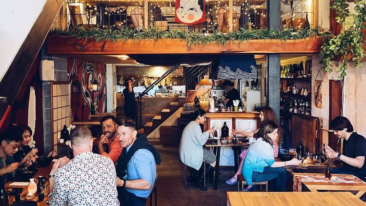 The interior dining area of Yoku Ono, with people seated and dining in groups.