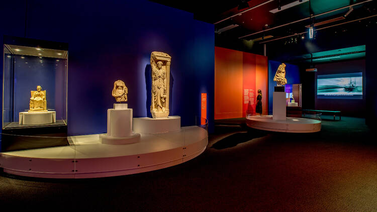 A gallery space featuring multiple ancient Greek artifacts on display