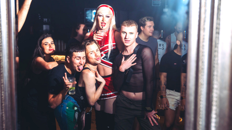 A group of friends and a drag queen pose for a photo at Fame Fridays at Universal
