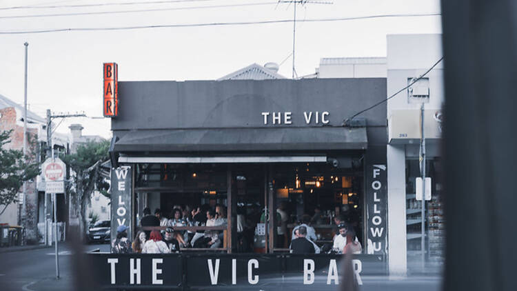 People sitting inside and out front of The Vic Bar.