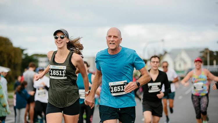 A man and a woman holding hands while running.