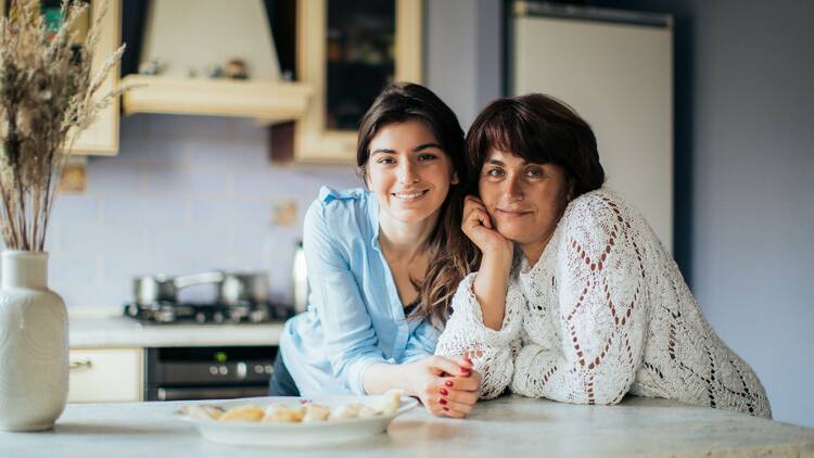 A mum and daughter leaning on a kitchen counter.