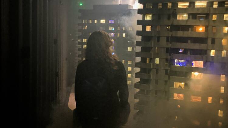 A woman stands in a room looking at realistic models of high rise buildings