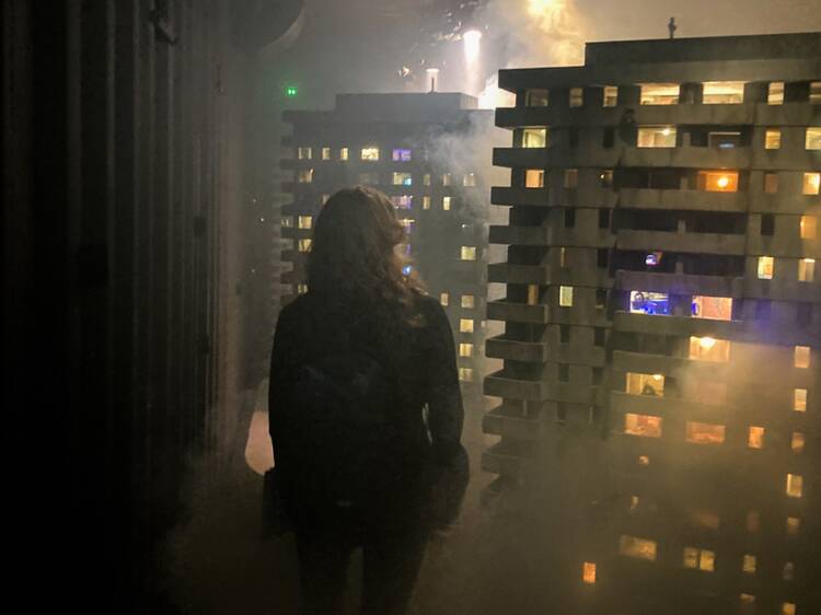 A woman stands in a room looking at realistic models of high rise buildings