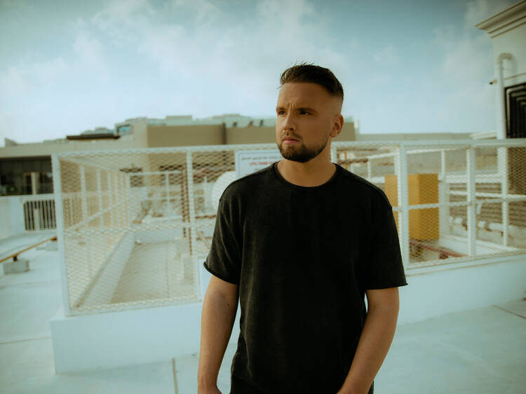 DJ Topic standing on a roof wearing a black shirt.