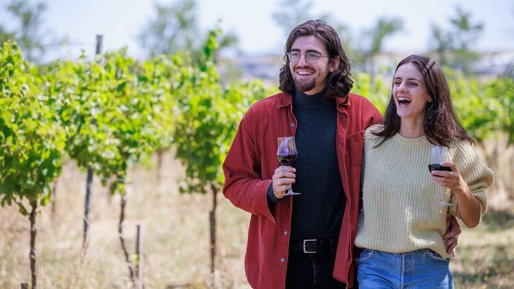 A couple with wine in a vineyard