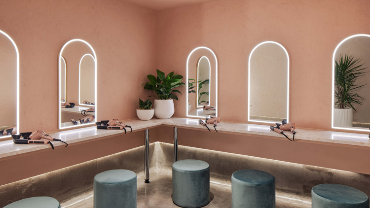 A peach dressing area with soft blue footstools and pink hairdryers at the gym
