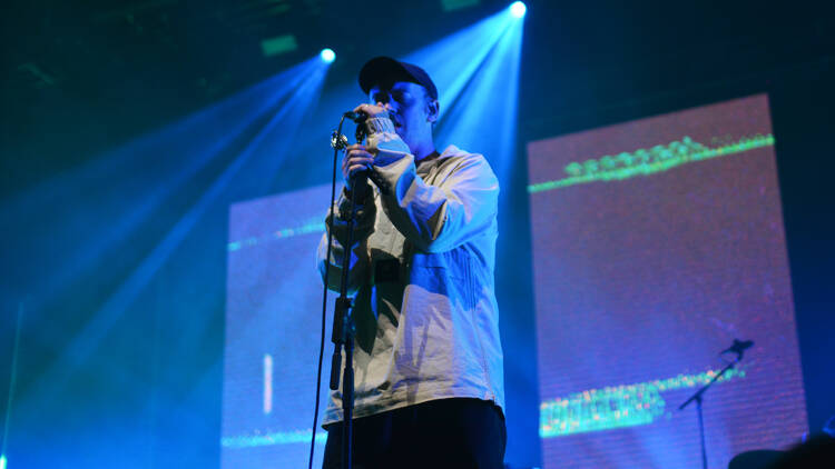 The lead singer of the DMA's singing into a microphone.