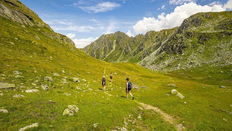 Three hikers walking in Swiss mountains.