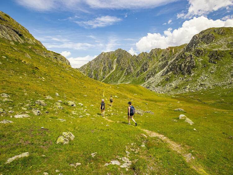 Three hikers walking in Swiss mountains.