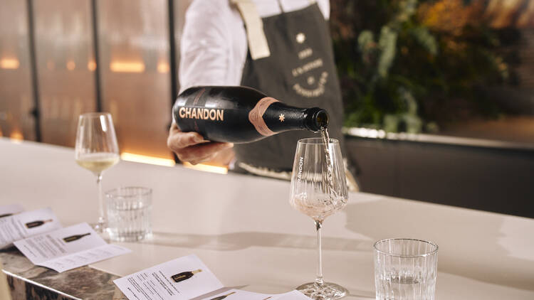 A bartender pouring Chandon sparkling wine into a glass.