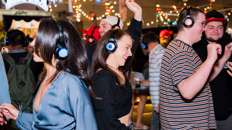 People dance with glowing headphones on at a silent disco