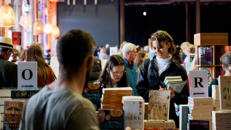 Two people hold books behind a stacked display at the Sydney Writer's Festival