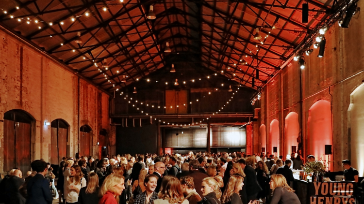 A picture of people gathering at night beneath strung fairy lights inside Carriageworks at the Sydney Writer's Festival