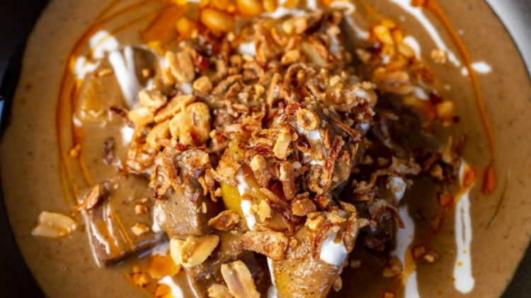 A bowl of massaman curry sprinkled with peanuts