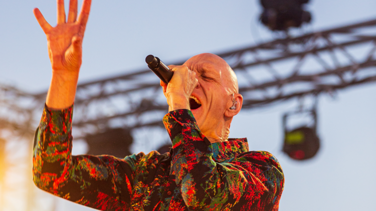 Peter Garret, lead singer of Midnight Oil sings into a microphone with his hand raised