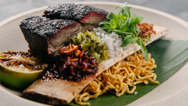 A slow-cooked beef dish with dried noodles and a charred lime.