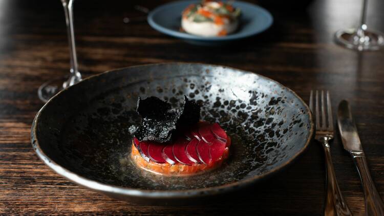 Trout tartare with yuzu, blood plum, squid ink cracker.