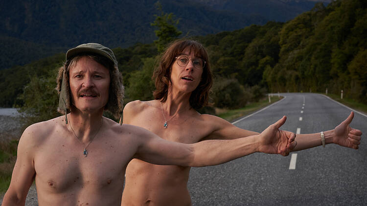 A still from the flick Nude Tuesday, featuring a nude man and woman hitchhiking.