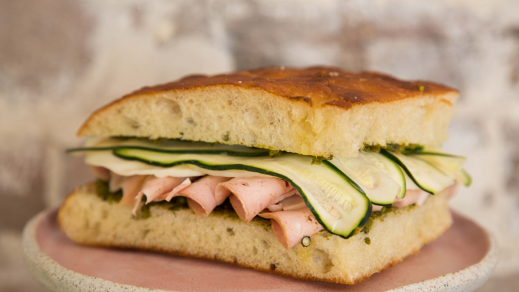 A large panini with zucchini and ham folded in it sits on a pink plate