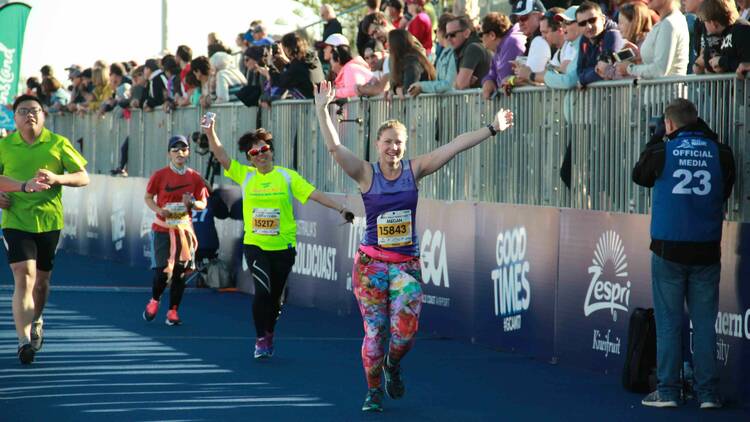 A woman running a marathon with other participants.