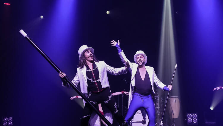 Two men in white top hats and white blazers holding canes.