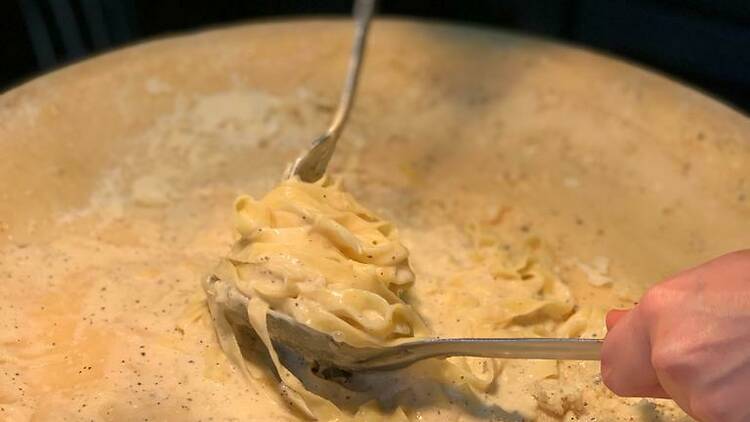 Pasta being twirled in a wheel of cheese