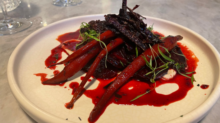 A dish of carrots with beetroot on a white plate.