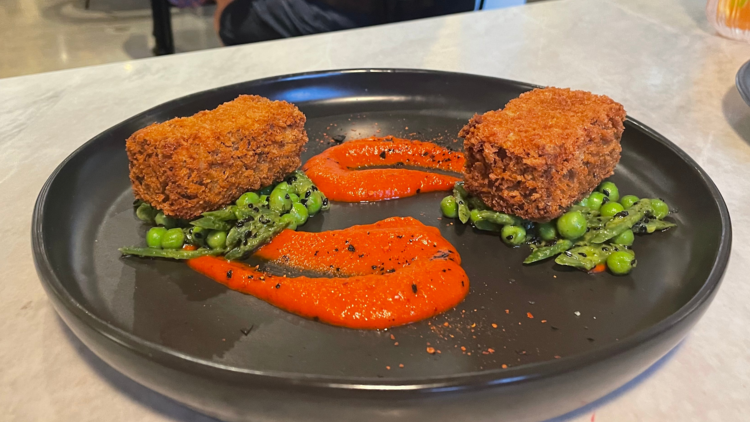 Cubes of battered and fried lamb atop peas and a sauce.