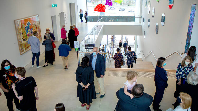 A crowd of people view art inside Shepparton Art Museum