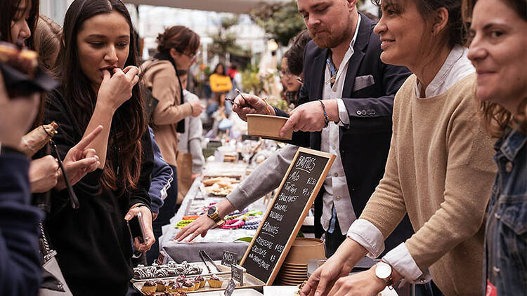 A group of people at a makers market sample some chocolates