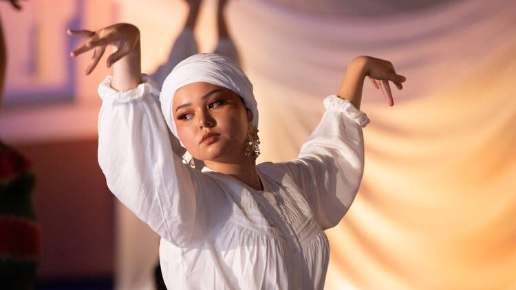 Woman dancing and performing in white traditional dress 