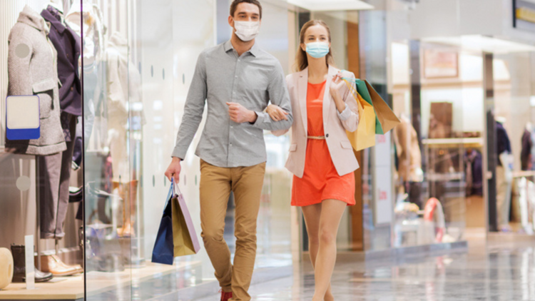 A masked couple walking through a shopping centre.