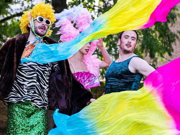 Thre people in drag, wigs and rainbow scarves