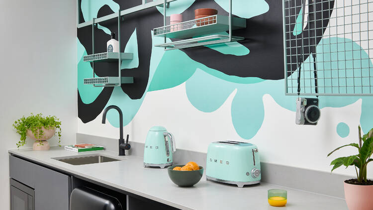 A teal-themed kitchen fitted out with Smeg appliances.