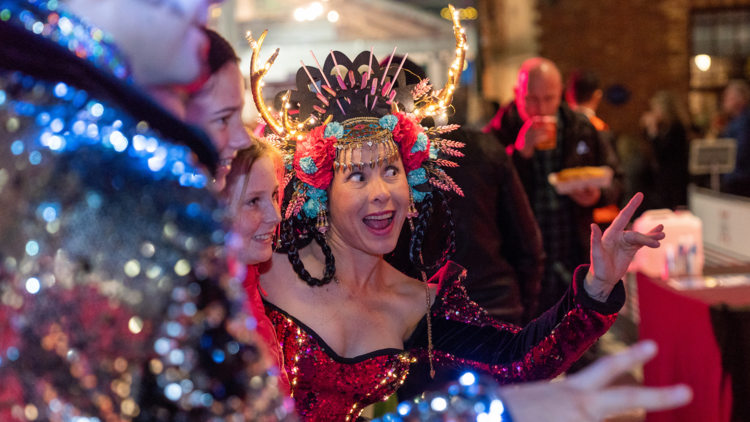 A woman wearing a multicoloured headdress with a joyful expression.
