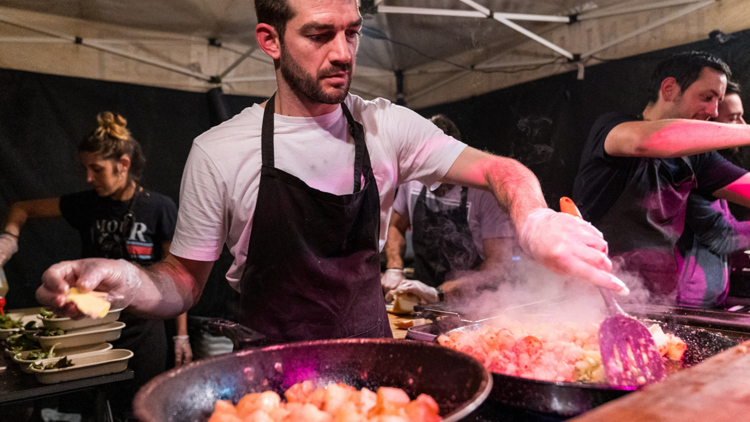 A man cooking paella at a night market.