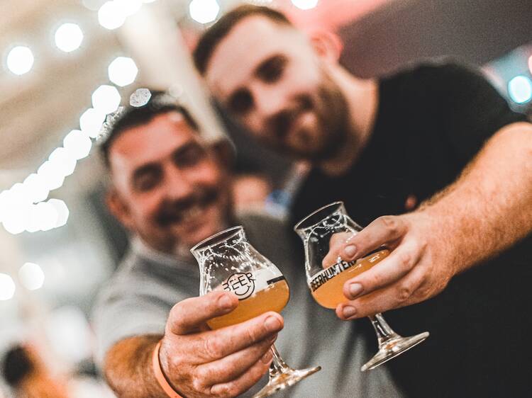 Two men hold up two glasses of beer