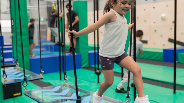 A little girl jumps on a rope walk at Ninja Parc in South Granville