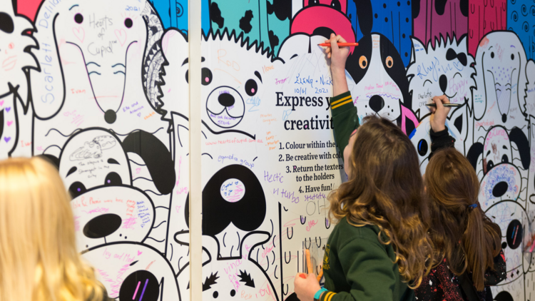 Kids draw on a community art wall at the Marrickville Metro