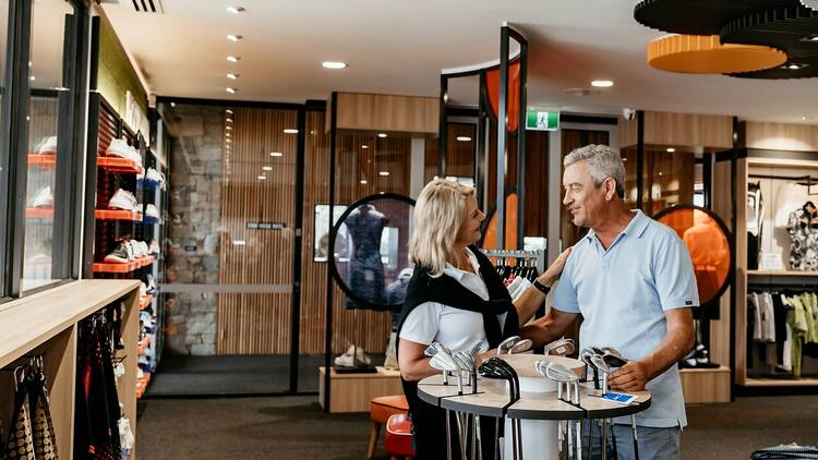 A woman and a man browsing goods in a golf pro shop.