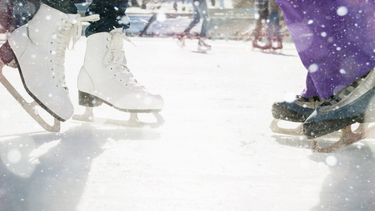 Feet in ice skates skate on a white ice floor