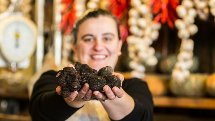 A woman holding handfuls of black truffles.