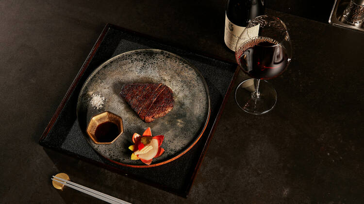 A steak on a plate with wine on the side