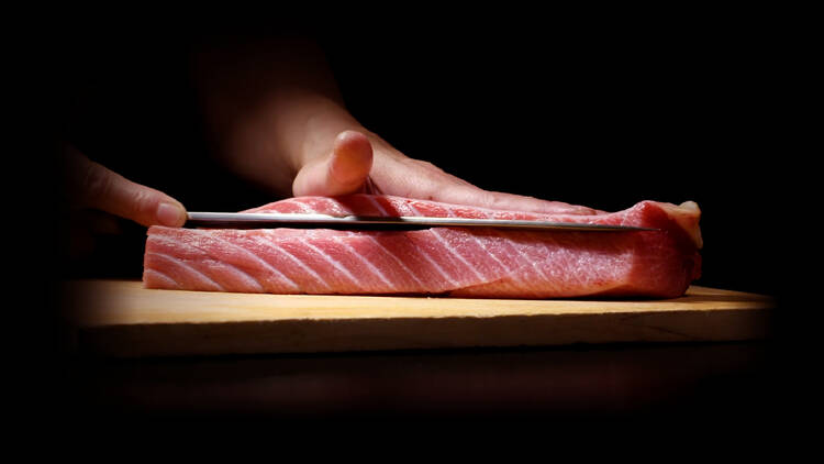A person slicing into a piece of bluefin tuna.